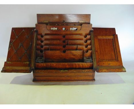 A good quality late 19th/early 20th century stained oak office compendium, the sloped front with brass lock revealing a fitte