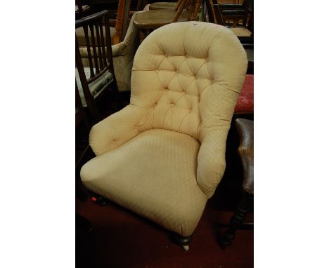 A Victorian cream upholstered button back armchair, raised on turned forelegs