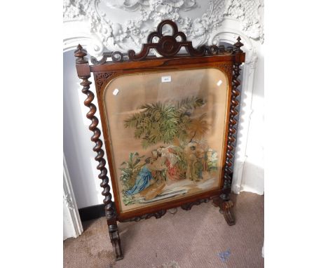 A VICTORIAN ROSEWOOD FIRE SCREEN with a needlework panel depicting figures in a religious scene, 41" high x 27" wide