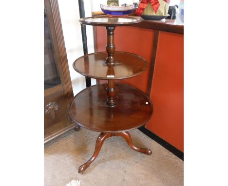 A GEORGE III MAHOGANY THREE TIER DUMB WAITER, with three revolving circular shelves above a tripod base on brass and leather 