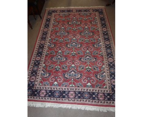 A PINK GROUND PERSIAN STYLE CARPET with blue border, 69" x 103" plus fringes
