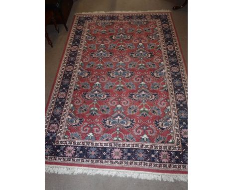 A PINK GROUND PERSIAN STYLE CARPET with blue border, 69" x 103" plus fringes