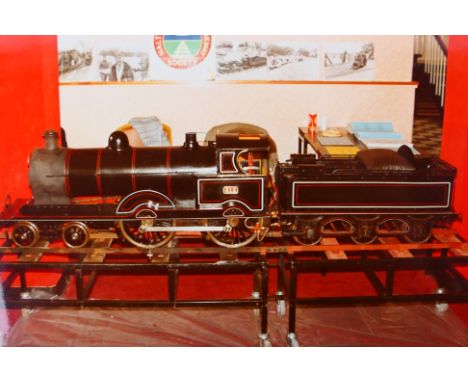 A live steam 7 1/4 inch gauge Bassett-Lowke style Precursor 4-4-0 steam locomotive, composing black body with red lining and 