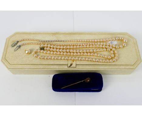 A rose metal and split pearl stick pin, stamped 15ct, 1.3 grams and two pearl bead necklaces contained in a Lotus box. [W]
