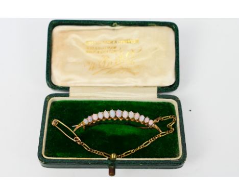 An antique rose metal and graduated opal crescent brooch, stamped 9ct and 375, with safety chain, 42 mm (l) and 2.6 grams. [W