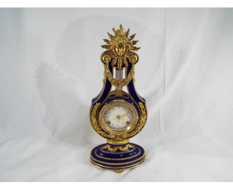 An unusual Victoria & Albert Museum porcelain and brass Marie Antoinette mantel clock, the enamel astronomical dial bearing R