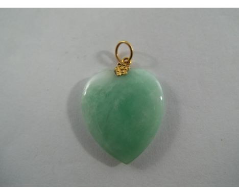 A heart shaped jade pendant with gold top.