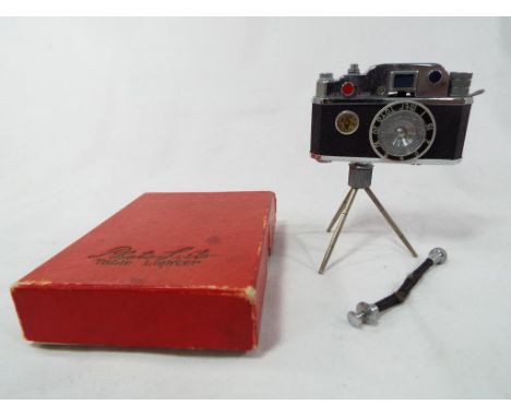 A mid 20th century novelty table top lighter in the form of a camera on tripod support, marked Photolite in original box with