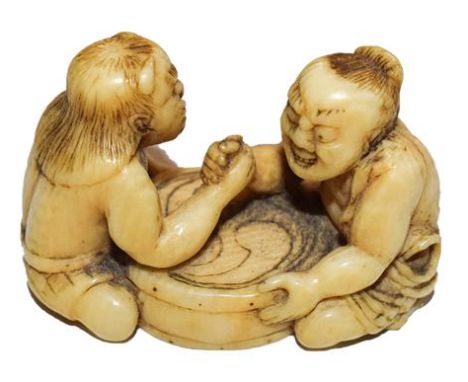 A Japanese Meiji period ivory netsuke in the form of arm wrestlers, signed to base