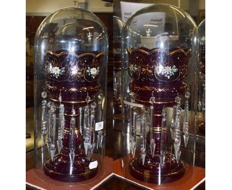 A pair of early 20th century ruby glass table lustres with gilt and enamel decoration, under glass domes, 48cm total height