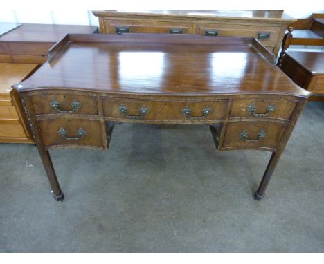 An Edward VII Chippendale Revival carved mahogany five drawer serpentine writing table 