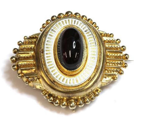A Victorian Etruscan Revival gold garnet and enamel shield form brooch, c.1860, a raised central oval boss with an oval caboc