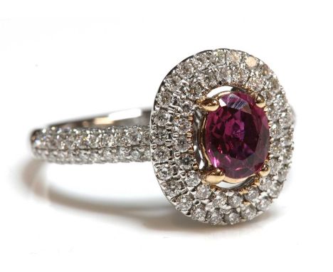 An 18ct rose and white gold, ruby and diamond two row halo cluster ring, an oval mixed cut ruby, with a stated weight of 0.85