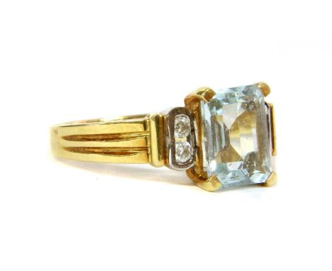 An 18ct gold aquamarine and diamond ring, an emerald cut aquamarine, claw set, with a pair of brilliant cut diamonds channel 