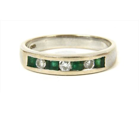 A white gold diamond and emerald half eternity ring, alternating brilliant cut diamonds and square step cut emeralds, all cha