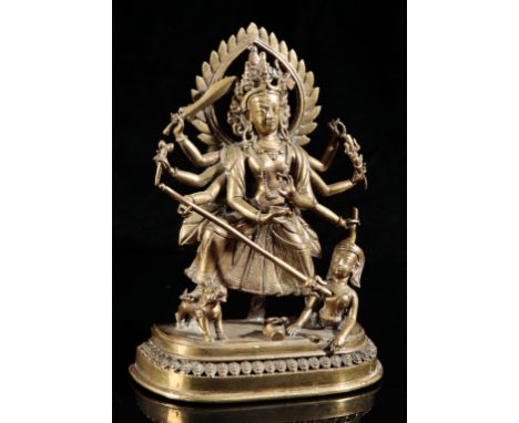A NEPALESE GILT BRONZE FIGURE OF DURGAQing dynasty, cast standing on a lotus base holding various weapons and implements in h