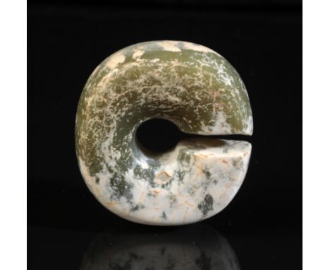 A CHINESE JADE SLIT RING probably Han dynasty, naively carved with multiple white inclusions, 3.8cm high x 4cm wide, in a fit