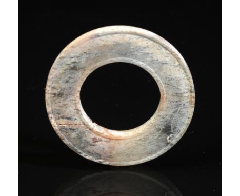 A CHINESE JADE RING probably Han dynasty, with moulded rims, lightly incised with scrolling and hatch decoration, 5cm diamete