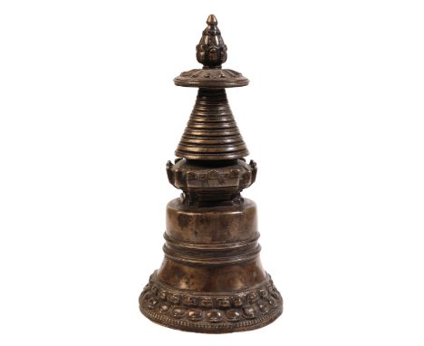 A TIBETAN BRONZE STUPApossibly 13th/14th century, of bell shaped form, the foliate finial above a castellated gallery, on a t