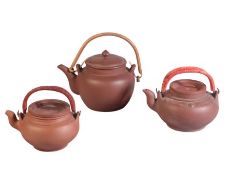 THREE CHINESE YIXING TEAPOTS including an example with bamboo loop handle and internal strainer, impressed seal mark to the b