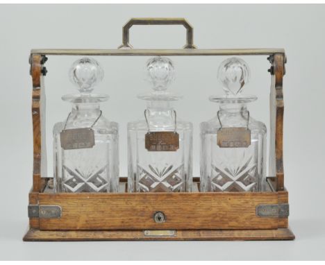 Edwardian oak and silver plated tantalus, by Mappin & Webb, the "cabinet tantalus" with three hallmarked silver decanter labe