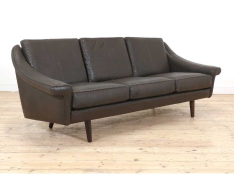 A Danish brown leather three-seater settee, the frame and cushions with stitched edges, raised on stained beech supports, 205