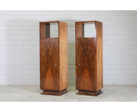 A pair of Art Deco walnut cabinets,the square tops over an open shelf, over a single book-matched cabinet door opening onto s