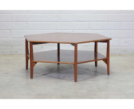 An hexagonal walnut coffee table,1970s, the top with a bevelled edge over a magazine shelf, raised on six supports, 106cm dia