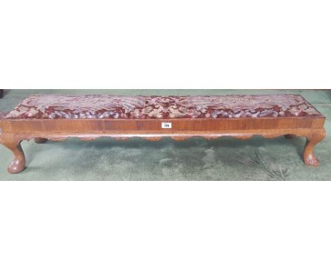 A Good Walnut Foot Stool with Original Tapestry Seat and Shaped Apron, 64 ins long.