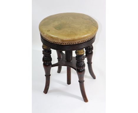 A late Regency faux rosewood brass mounted piano stool, with revolving leather covered circular seat, on ring turned, lobed a