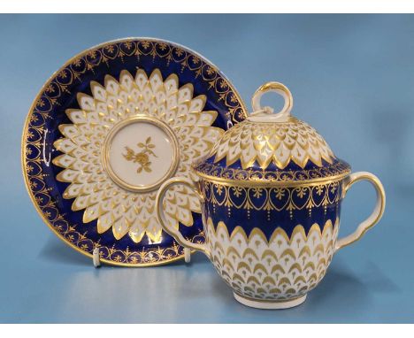 A Derby two handled cup, cover and saucer with royal blue rims enclosing gilt and moulded feathered decoration, blue mark, pr