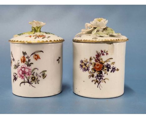 Two Derby cylindrical ointment pots and covers painted with flowers, the covers with flower and leaf finials, patch marks, RF