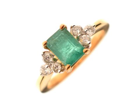 Emerald and diamond dress ring, the emerald cut claw set with a trio of diamonds to each shoulder, the yellow metal shank sta