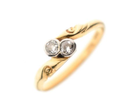 Two-stone diamond crossover ring, the two diamonds rubover set in white metal, the yellow metal shank stamped '18ct Plat', si