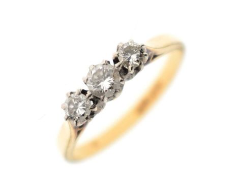 Three-stone diamond ring, the three brilliant cut diamonds claw set in white metal, the yellow metal shank stamped '18ct &amp