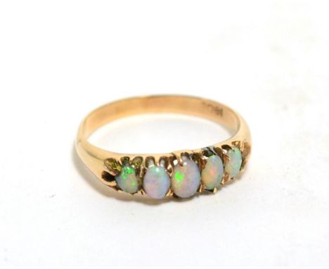 An opal five stone ring, graduated oval opals in claw settings, finger size O, stamped '18CT'Chips noted to the two outer opa