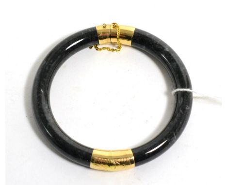 A black dyed hardstone bangle with foliate engraved mounts, stamped '14K'