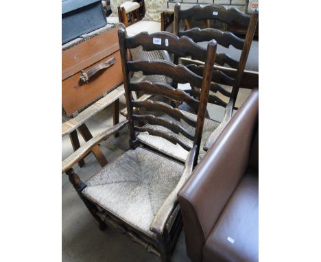 A pair of oak rush seated ladder back elbow chairs.