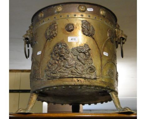 A large brass and copper log bin with lion ring handles and paw feet.