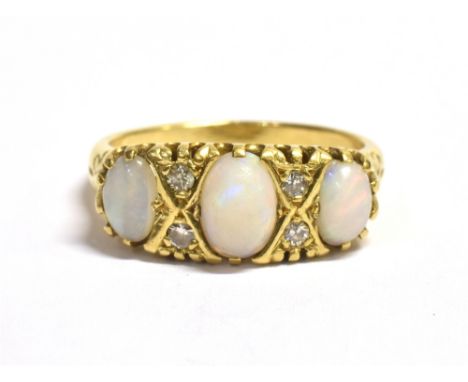 A STAMPED 18CT OPAL TRIPLE STONE, DIAMOND ACCENT DRESS RING the ring set with three opals, light but with play of colours, ce