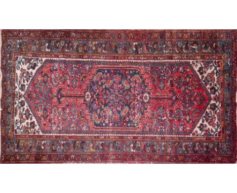 An Iranian rug with central geometric lozenge medallion, on a red ground, contained by floral border, 190 x 107cm 