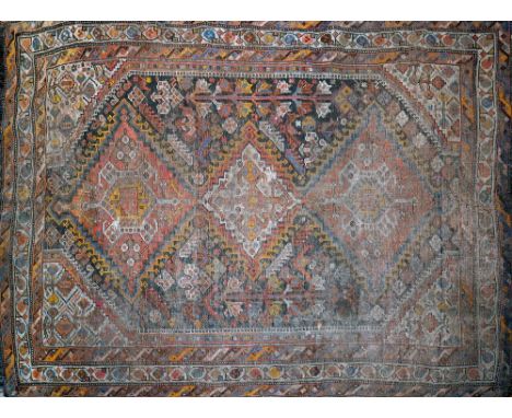 An antique Persian carpet with triple geometric diamond medallion surrounded by geometric motifs, on a black ground, containe