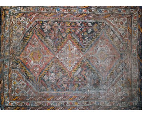 An antique Persian carpet with triple geometric diamond medallion surrounded by geometric motifs, on a black ground, containe