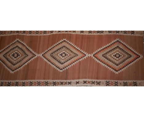 A large Turkish kelim runner with triple geometric medallion, on a brown and beige ground, contained by geometric border, 422