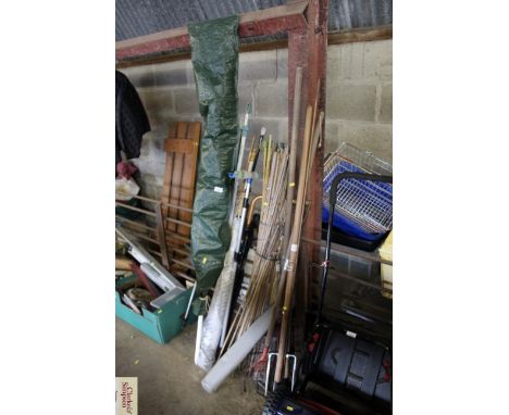 A quantity of long handled garden tools; garden canes; a parasol etc.