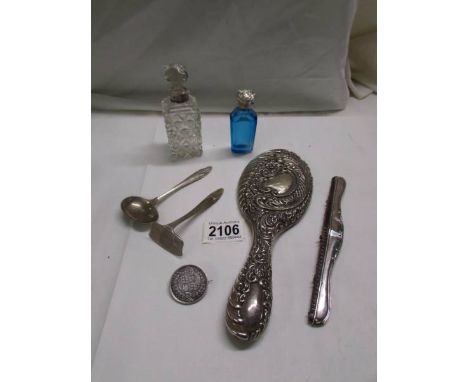 A silver spoon with pusher, a silver backed hand mirror, 2 silver topped scent bottles, a Victorian silver coin brooch and an