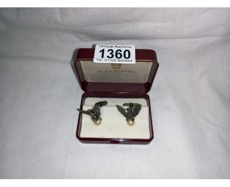 A pair of American Eagle cufflinks with eagles sitting on a pearl. 