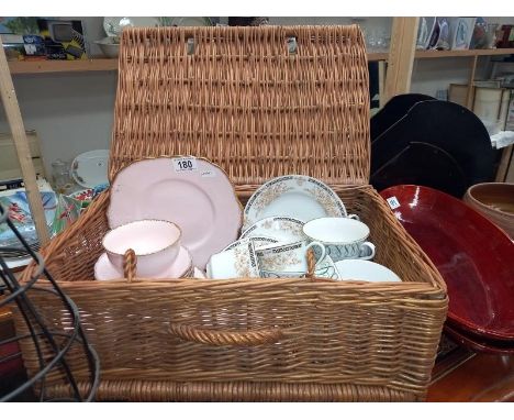 A wicker hamper basket with mixed part tea sets.