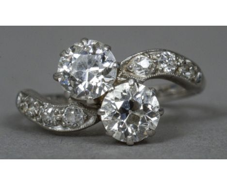 A platinum and diamond crossover ring
The twin claw set stones flanked by diamond set shoulders.  CONDITION REPORTS: Shank sl