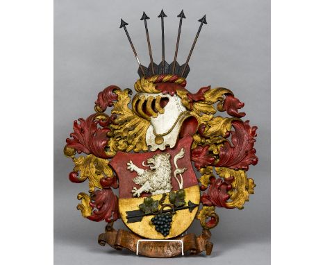 A carved and painted wood heraldic crest
The shield worked with a lion and fruiting vine mounted arrow, surmounted with a hel